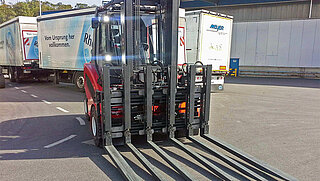 Une machine de construction avec un large accessoire à six dents à l'extérieur d'une usine