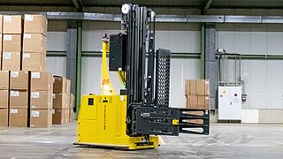 Vue latérale d'un chariot autoguidé jaune avec accessoire dans un entrepôt