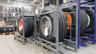 Einzelne Flugzeugreifen sind einzeln in Metallgestellen und in großen Mengen in Regalen gelagert