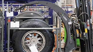 A round fork clamp moves towards a stored aircraft tyre to pick it up and transport it
