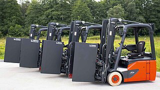 Quatre chariots élévateurs en ligne, chacun équipé de l'accessoire Smart Load Control