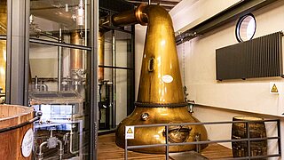 Vista frontal de un alambique de cobre para destilar whisky en una fábrica de bebidas alcohólicas