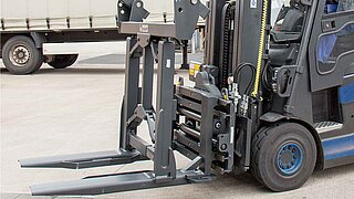 Side view of a blue forklift truck with mounted attachment with two tines