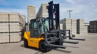 Una carretilla elevadora amarilla con una pinza doble especial para ladrillos almacenados