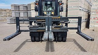 Front view of an unloaded forklift truck with four flat forks in a storage yard