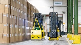 Automated guided vehicles move along a high wall of boxes through an aisle