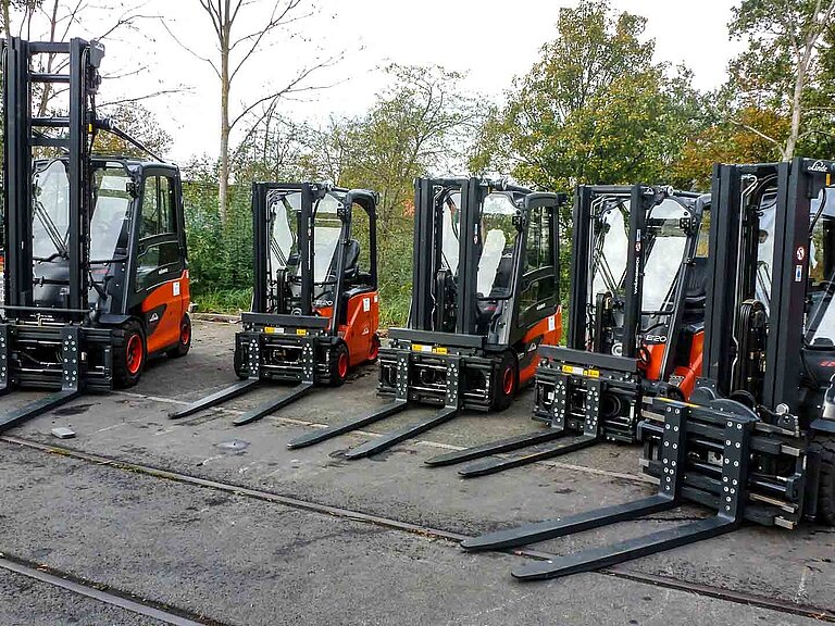 Cinco carretillas elevadoras rojas con accesorios idénticos están aparcadas en semicírculo