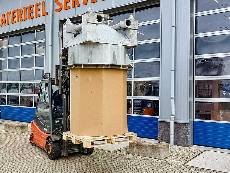 A red forklift truck takes a large cylindrical roll on a pallet onto the fork