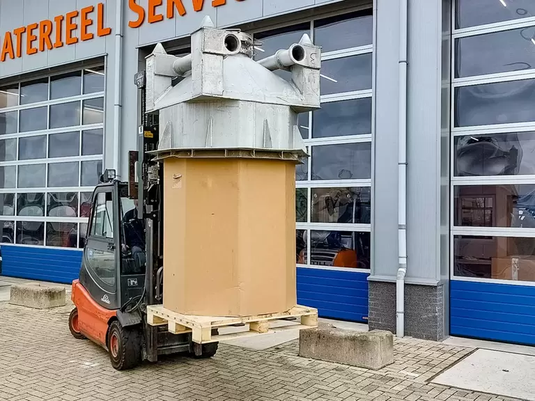 A red forklift truck takes a large cylindrical roll on a pallet onto the fork