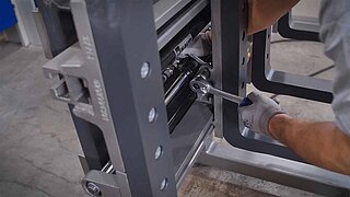 A maintenance technician with a socket spanner tightens a screw on a clamp fork