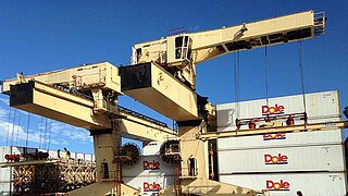 Two large yellow cranes with several stacked containers in the background