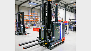 Several driverless black forklifts in a factory against a blurred background
