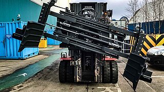 Vista frontal de una máquina de construcción con la pinza de pacas extendida y ligeramente girada