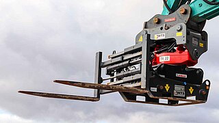View of the top of a crane with mounted fork positioner against a cloudy sky