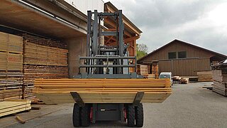 Der integrierte Kippgabelträger von KAUP bei seiner Hauptaufgabe: Dem innerbetrieblichen Transport von Holzpaketen.