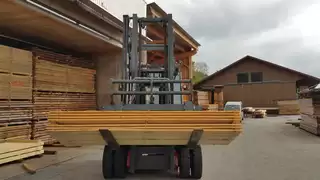 Der integrierte Kippgabelträger von KAUP bei seiner Hauptaufgabe: Dem innerbetrieblichen Transport von Holzpaketen.