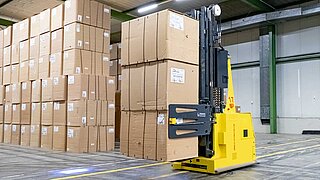 A driverless transport system transports three large cartons with one clamp through a warehouse