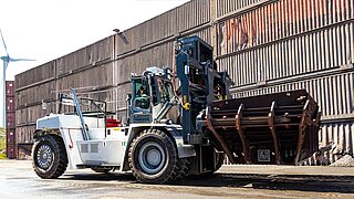 Une grande machine transporte un conteneur de scories avec un accessoire spécial