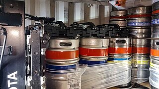 View into a container with several silver beer barrels wrapped with platics