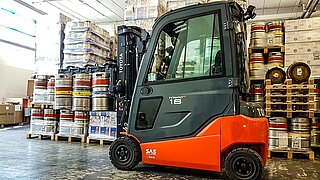 Forklift truck with flat attachment without forks and a multitude of stacked barrels in background