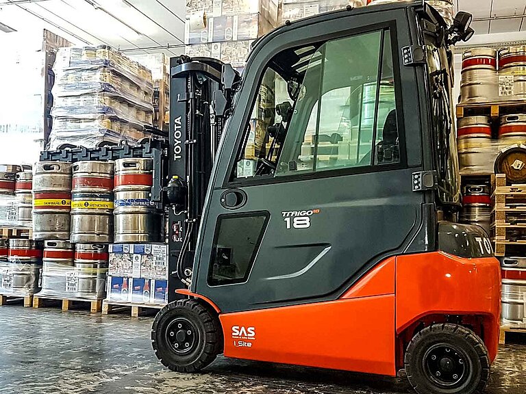 Forklift truck with flat attachment without forks and a multitude of stacked barrels in background