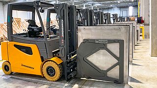 Mehrere gelbe Gabelstapler, geparkt in einer Reihe, jeweils mit Smart Load Control Anbaugerät