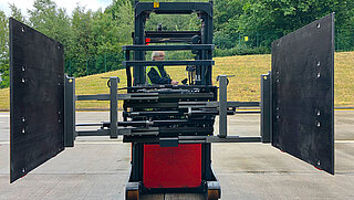 Front view of a red forklift truck with driver and mounted Smart Load Control attachment