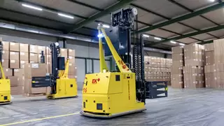 Mehrere fahrerlose Transportsysteme mit Kartonklammern manövrieren durch eine Lagerhalle