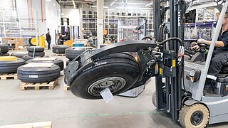 Un chariot élévateur à pince arrondie transporte un pneu d'avion dans un entrepôt