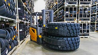 Automated guided vehicles move along a high wall of boxes through an aisle