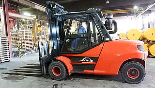 Vista lateral de una máquina de construcción roja con un accessorio de carretilla elevadora