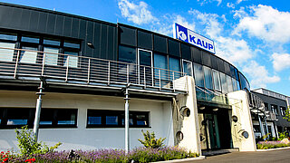 Vista exterior de la sede de KAUP con una vista de la entrada y el logotipo de KAUP sobre ella