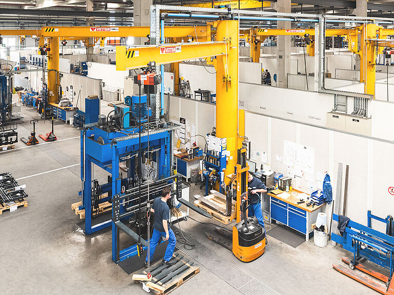 Mehrere Mitarbeiter überwachen die Herstellung von Anbaugeräten in einer Fabrikanlage von KAUP