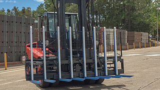 Baumaschine mit montierem Anbaugerät, welches als Spezialanfertigung über 8 Gabelzinken verfügt