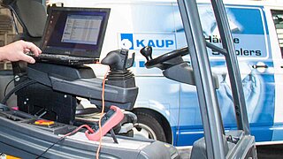 Vista de la cabina del conductor de una carretilla elevadora con un transportador de KAUP al fondo