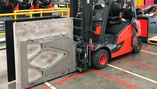Ein roter Gabelstapler, ausgestattet mit Smart Load Control Anbaugerät, geparkt in einem Fabriklager