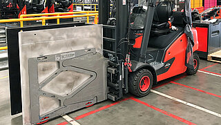 A red forklift truck equipped with Smart Load Control attachment parked in a factory warehouse