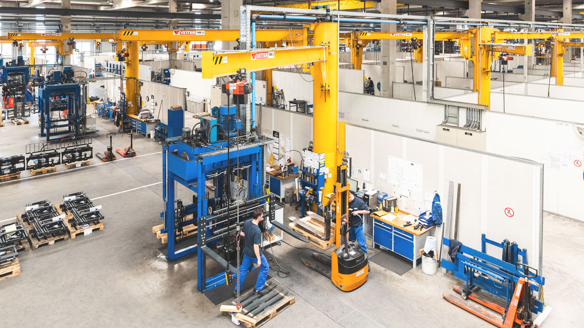 Mehrere Mitarbeiter überwachen die Herstellung von Anbaugeräten in einer Fabrikanlage von KAUP