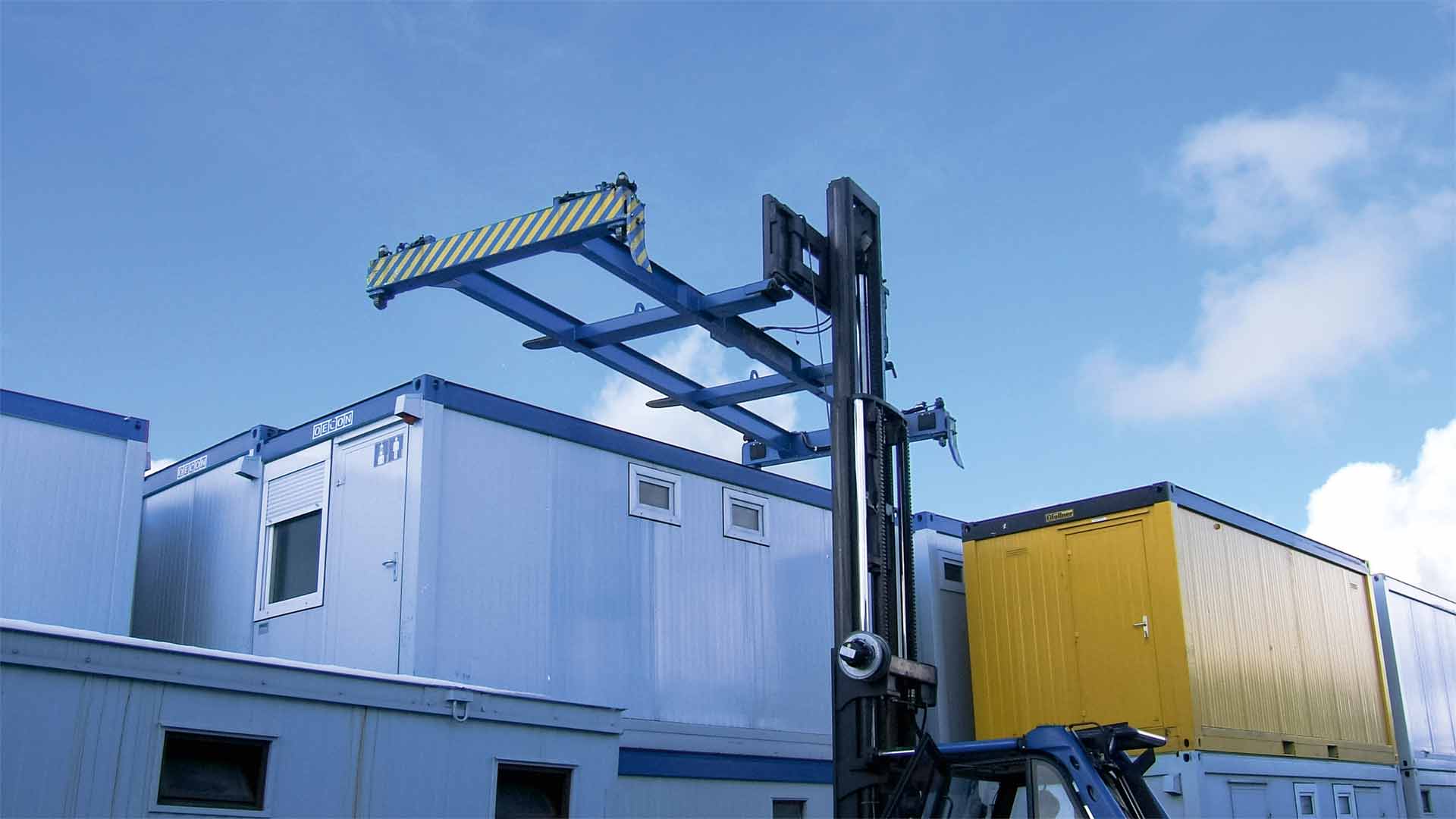 Ein ausgefahrener blauer Container-Spreader schwebt über bunten, gestapelten Containern