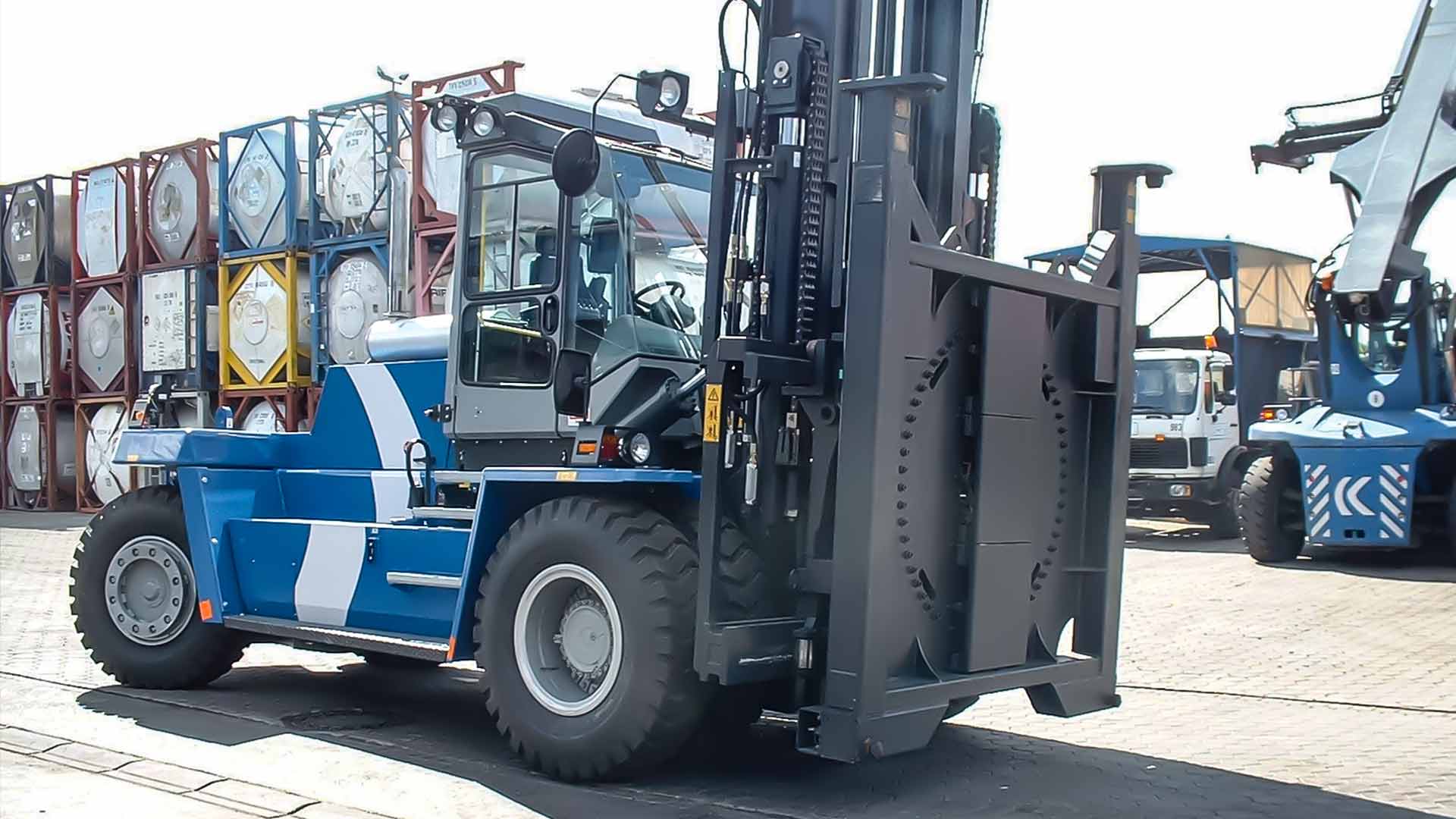 Blue forklift truck with flat rotating attachment in front of stacked containers
