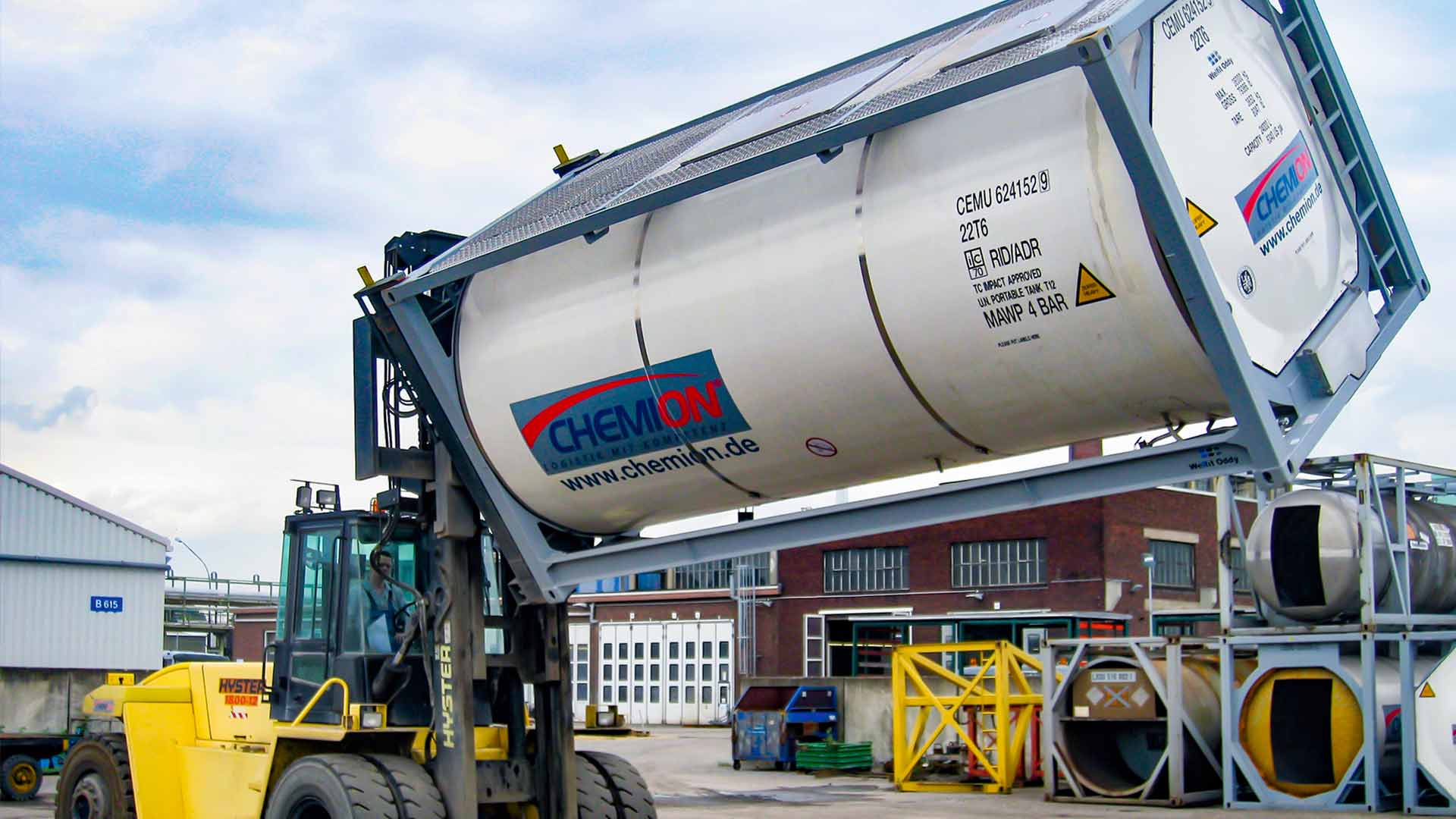 A yellow forklift truck lifts an empty container with the help of a rotating attachment