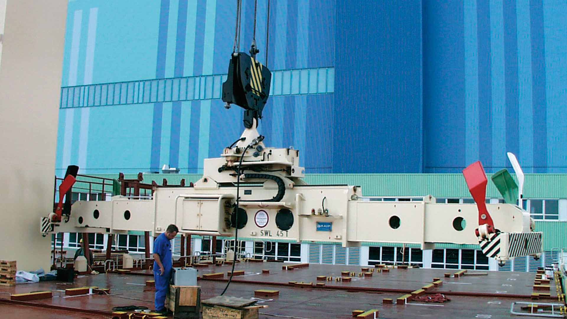 A large container spreader from KAUP in the field with the operator in the foreground