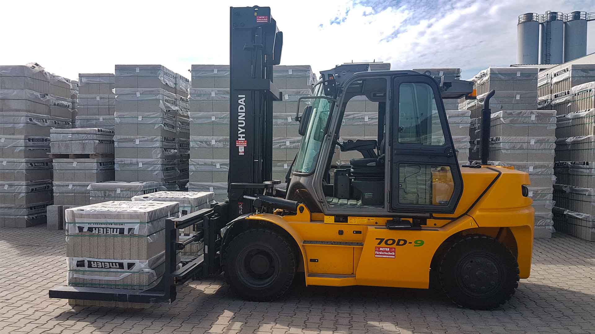 Eine Baumaschine mit speziellem Anbaugerät beim Transport mehrerer Steinpakete