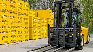 A forklift truck with Six Pallet Handler in front of a mountain of packages with aerated concrete