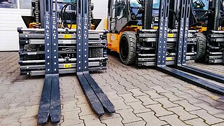 Several yellow forklifts with identical four-pronged attachments are parked next to each other