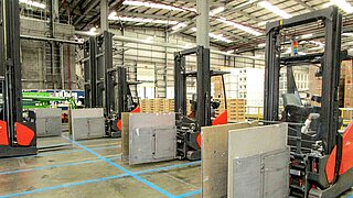 Several forklift trucks with identical attachments face each other in a row