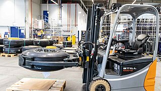 A forklift truck lifts an aircraft tyre for transport through a warehouse using a clamp fork