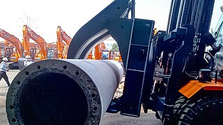 Side view of a mounted roller clamp in the process of transporting a pipe