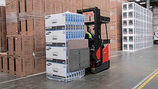 Forklift truck transporting LED TVs in front of piled up packaged electronic products