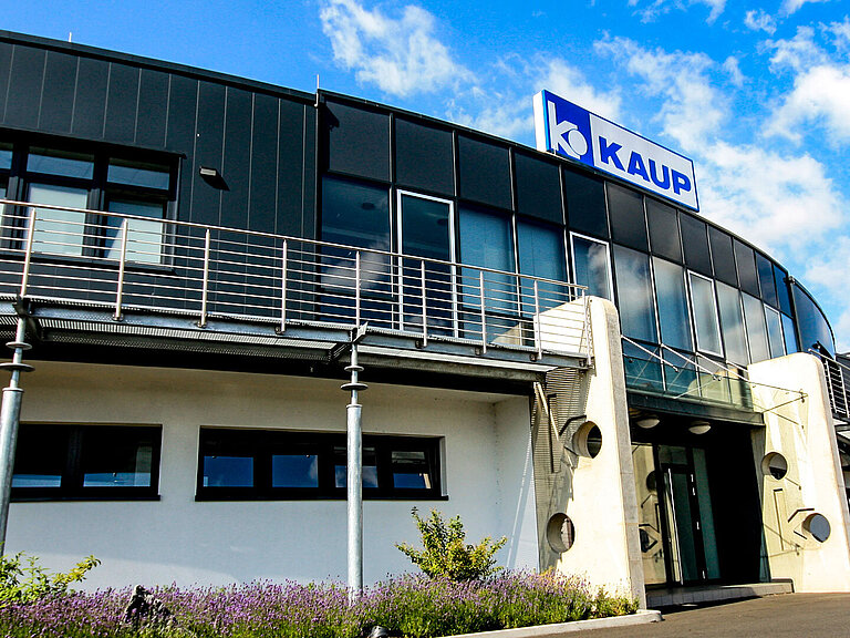 Vista exterior de la sede de KAUP con una vista de la entrada y el logotipo de KAUP sobre ella